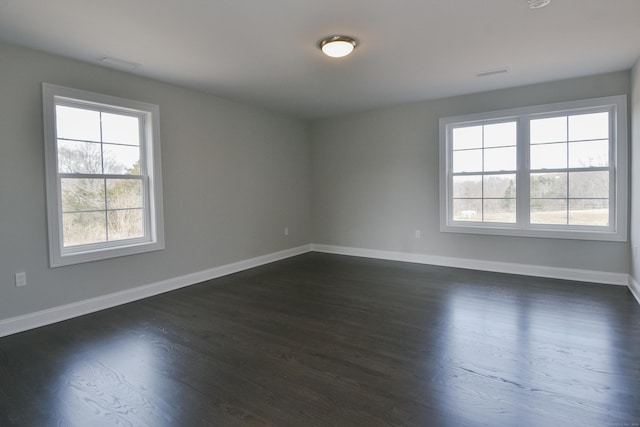 spare room featuring visible vents, dark wood-style floors, and baseboards