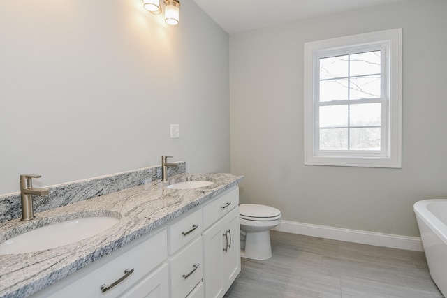 full bath featuring a sink, baseboards, a soaking tub, and double vanity