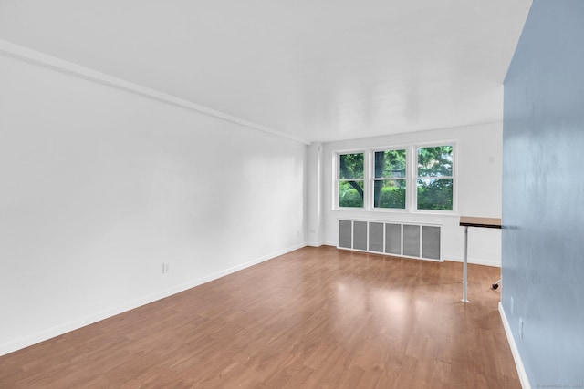 unfurnished living room featuring wood-type flooring and radiator