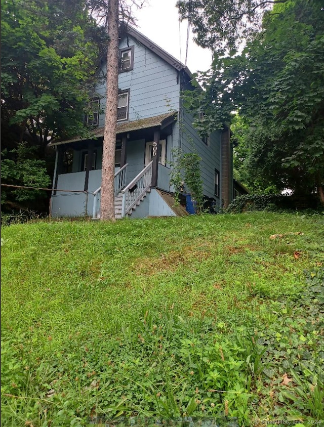 exterior space featuring covered porch and a lawn