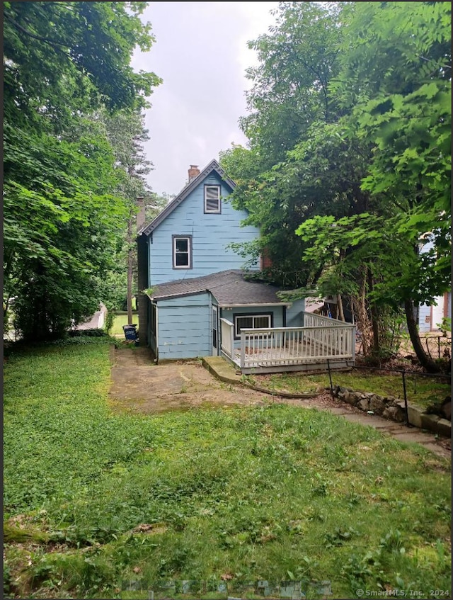 rear view of house with a deck, a lawn, and a garage