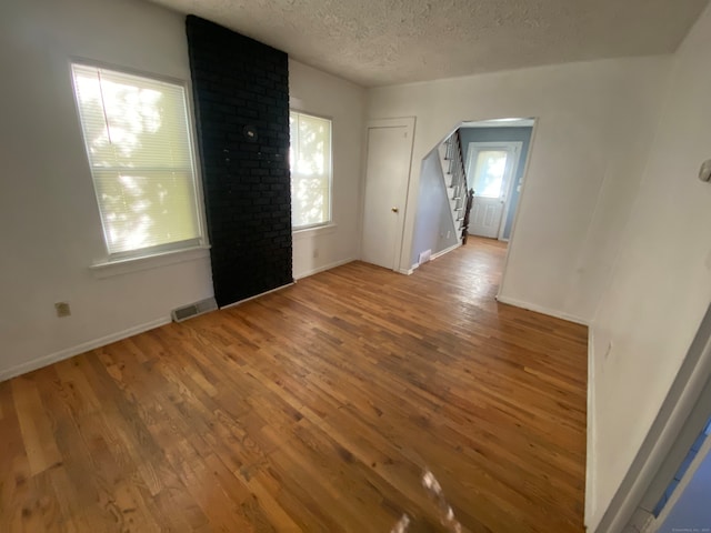 spare room featuring a textured ceiling, wood-type flooring, and a wealth of natural light