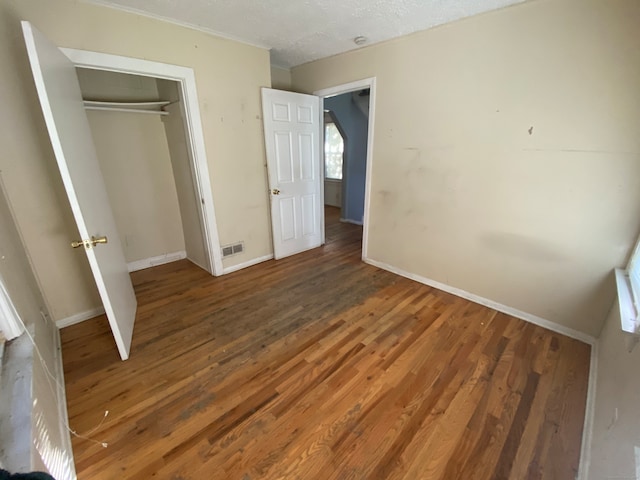 unfurnished bedroom featuring a closet, a textured ceiling, and dark wood-type flooring