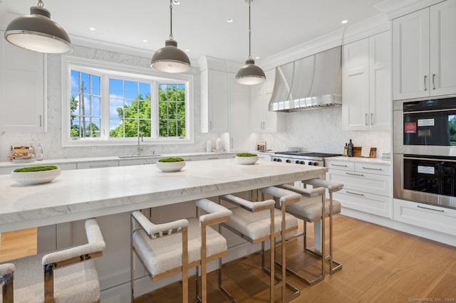 kitchen featuring appliances with stainless steel finishes, light stone counters, premium range hood, backsplash, and light wood-type flooring