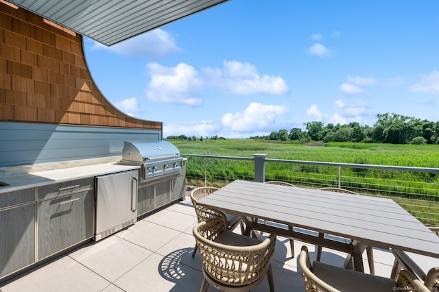 view of patio with grilling area, a rural view, and exterior kitchen