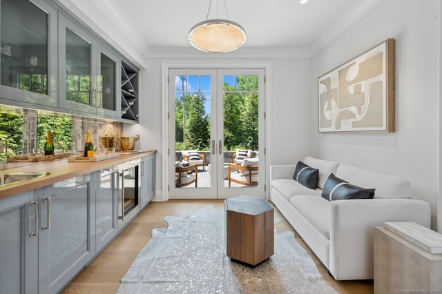 living room with ornamental molding, french doors, light wood-type flooring, and beverage cooler