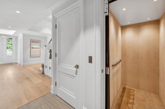 corridor featuring light hardwood / wood-style floors, a barn door, and elevator