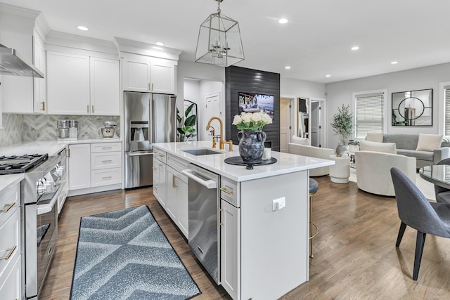 kitchen featuring stainless steel appliances, a sink, open floor plan, light countertops, and a center island with sink