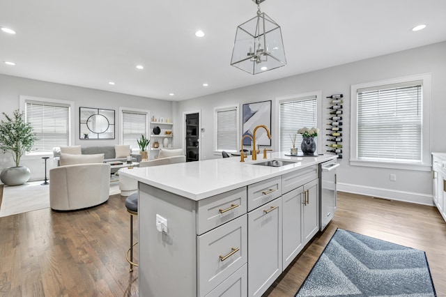 kitchen featuring recessed lighting, light countertops, dark wood-type flooring, open floor plan, and a sink