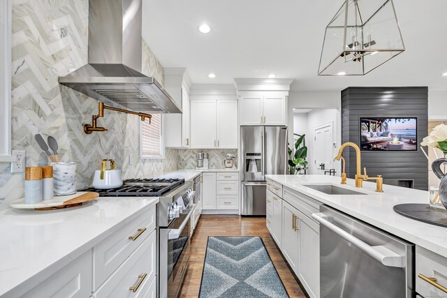 kitchen with stainless steel appliances, a sink, white cabinetry, light countertops, and wall chimney exhaust hood