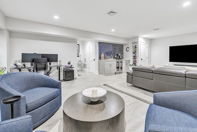 living area featuring recessed lighting, visible vents, light wood-style flooring, and a bar