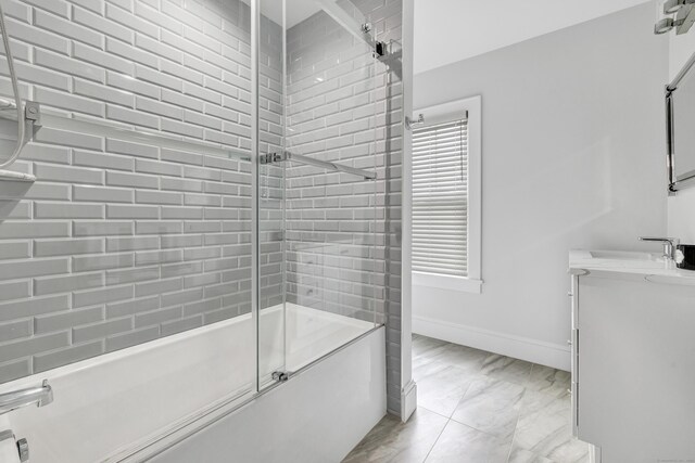 bathroom featuring marble finish floor, shower / bath combination with glass door, a wealth of natural light, and baseboards