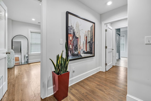 corridor with baseboards, wood finished floors, and recessed lighting