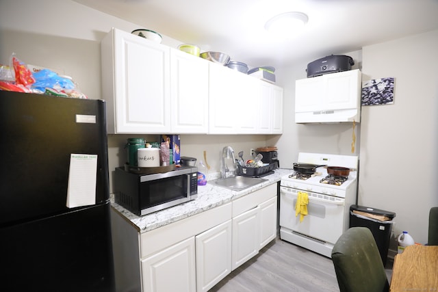 kitchen featuring white range with gas cooktop, sink, light hardwood / wood-style floors, black refrigerator, and white cabinetry