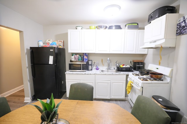 kitchen with white cabinets, sink, black refrigerator, light hardwood / wood-style floors, and white gas stove