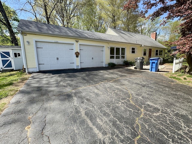 view of front of property with driveway, a chimney, a shingled roof, and a garage