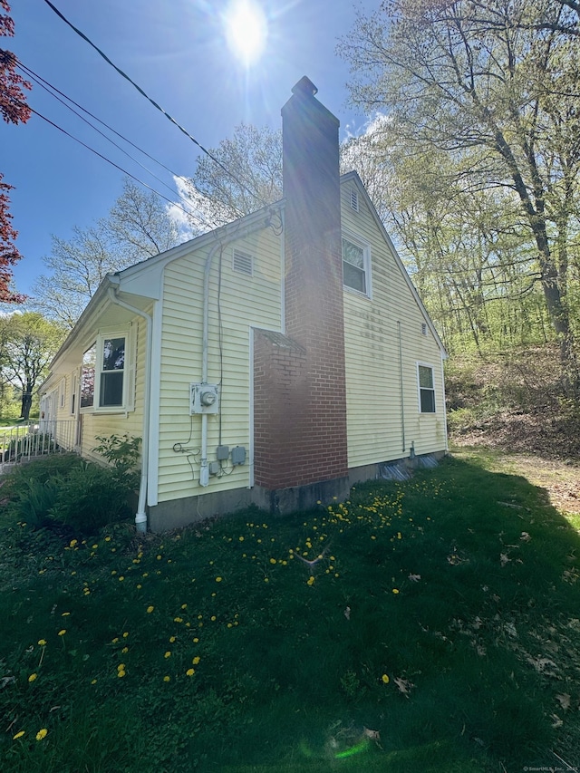 view of property exterior featuring a yard and a chimney