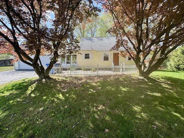 ranch-style home with a garage, a fenced front yard, and a front yard