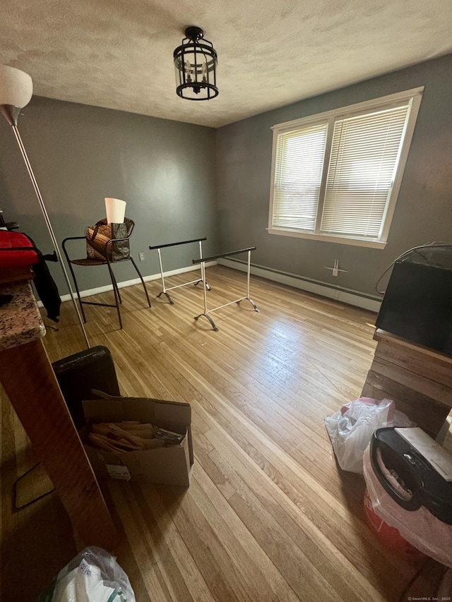 miscellaneous room with baseboards, a textured ceiling, a baseboard heating unit, and wood finished floors