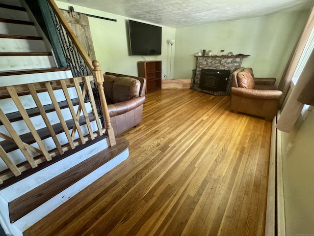 living room with wood-type flooring, a textured ceiling, a fireplace, and stairway