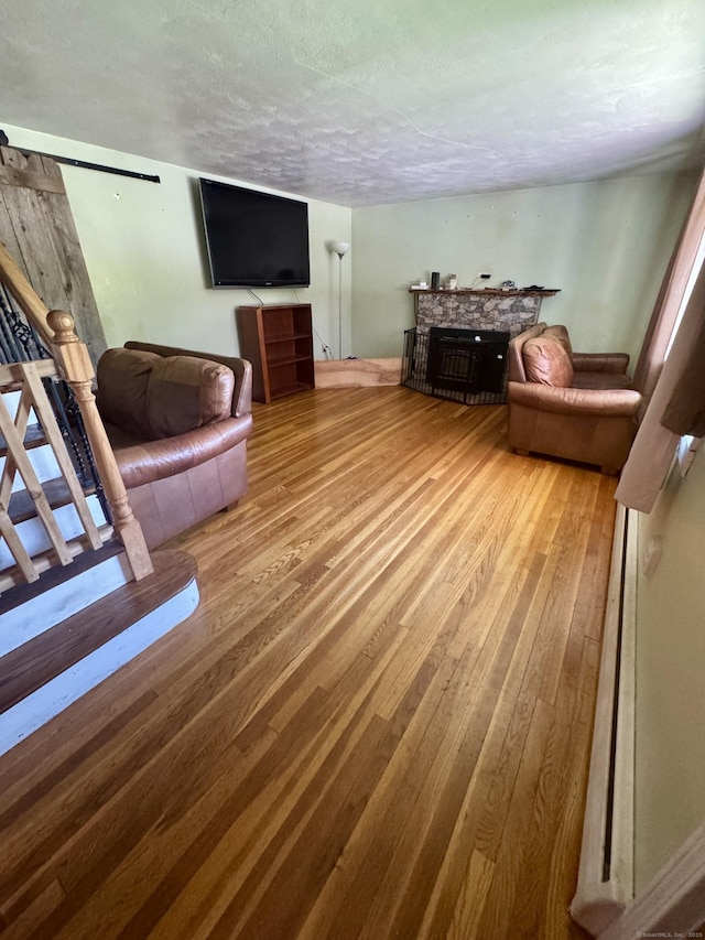 living area featuring a textured ceiling, a fireplace, hardwood / wood-style flooring, and stairway