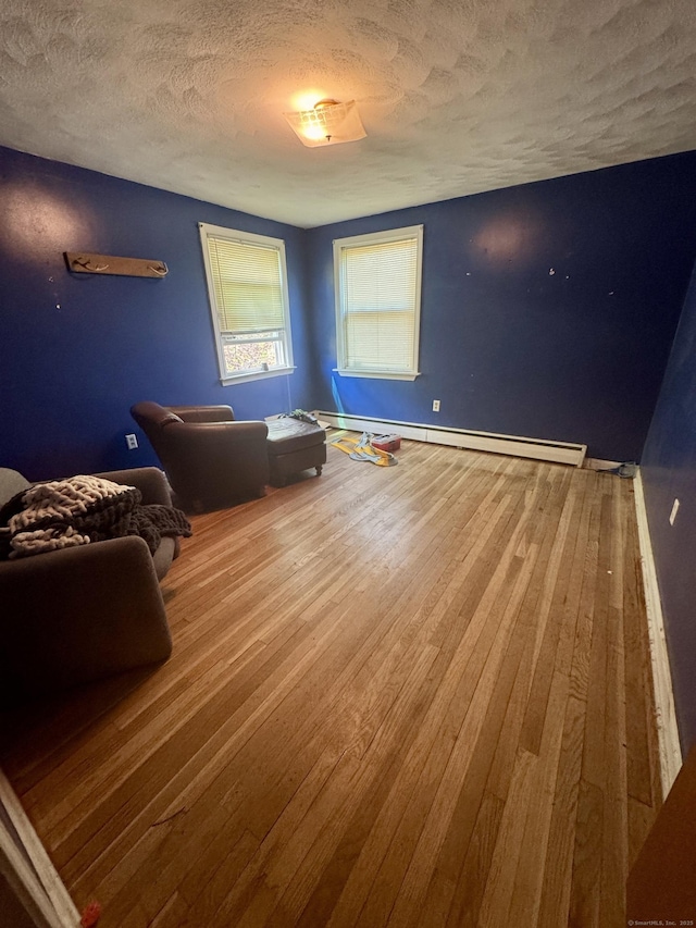 interior space with wood-type flooring, a textured ceiling, and a baseboard heating unit
