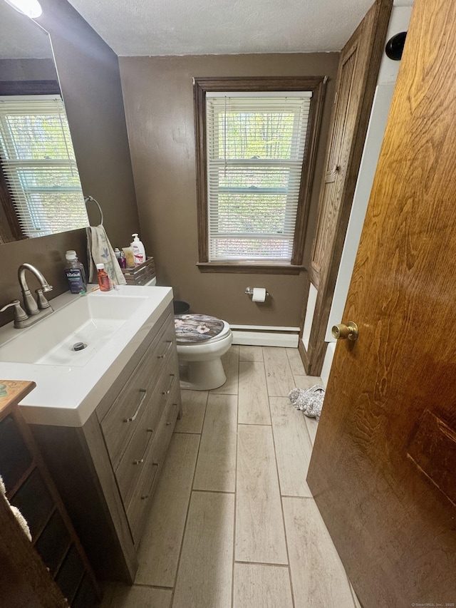 bathroom with baseboard heating, toilet, wood finished floors, and vanity