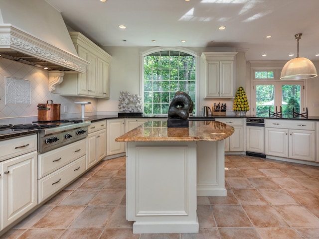 kitchen featuring tasteful backsplash, stainless steel gas stovetop, dark stone countertops, custom exhaust hood, and hanging light fixtures