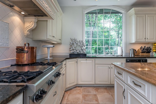 kitchen featuring premium range hood, sink, stainless steel gas cooktop, white cabinetry, and dark stone counters