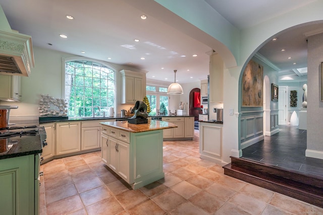 kitchen featuring dark stone counters, hanging light fixtures, a center island, kitchen peninsula, and crown molding