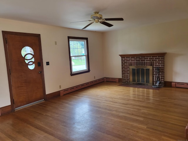 unfurnished living room with hardwood / wood-style flooring, a baseboard radiator, a brick fireplace, and ceiling fan