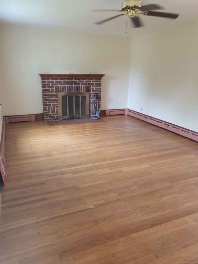 unfurnished living room featuring a brick fireplace, baseboard heating, light hardwood / wood-style floors, and ceiling fan