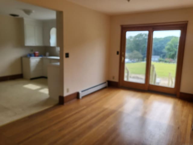 unfurnished room featuring light hardwood / wood-style floors and a baseboard heating unit