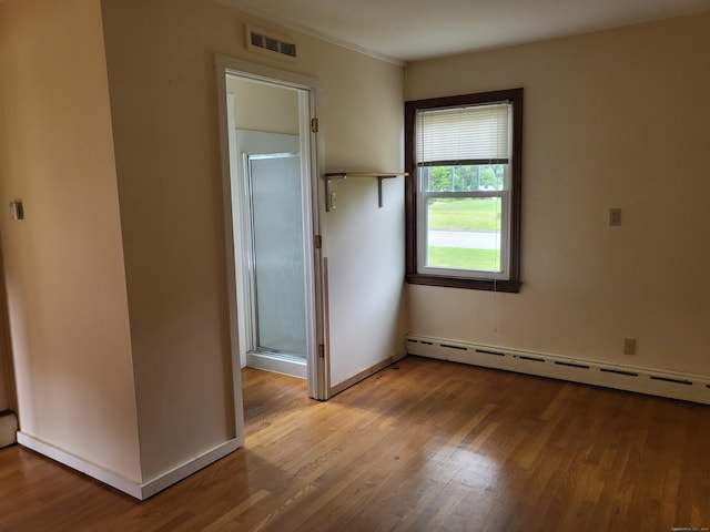 unfurnished bedroom featuring baseboard heating and light hardwood / wood-style floors