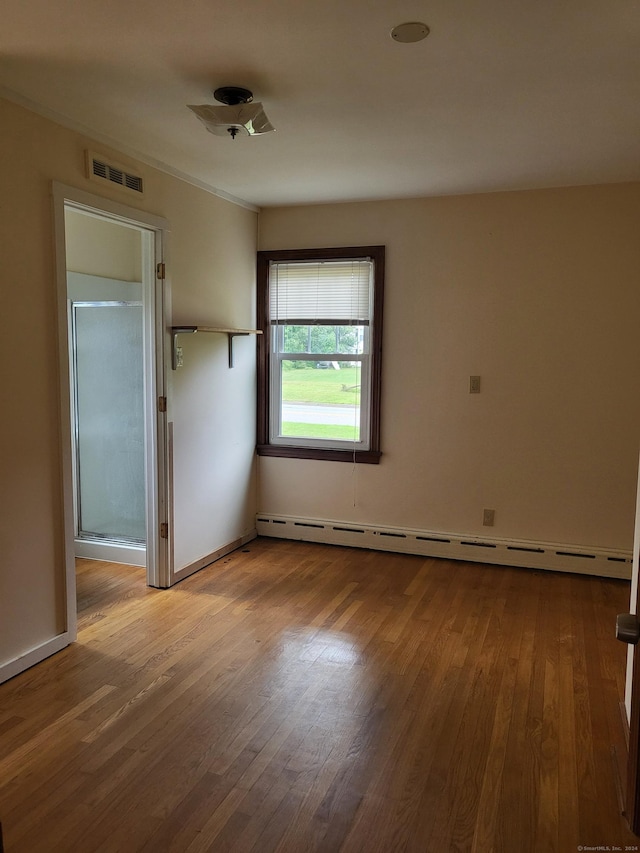 spare room featuring a baseboard radiator and wood-type flooring