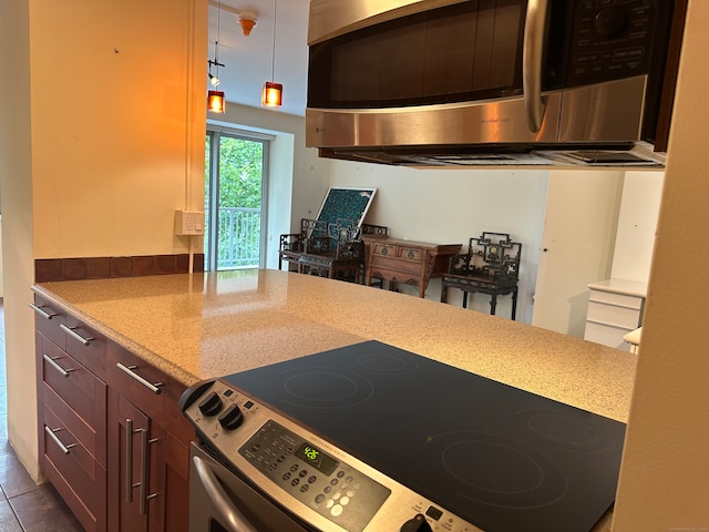 kitchen featuring tile patterned floors, light stone counters, stainless steel appliances, and decorative light fixtures