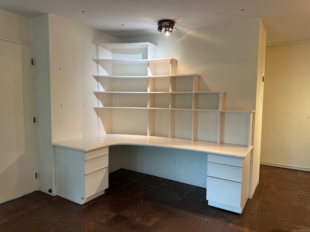 unfurnished office featuring built in desk and dark tile patterned flooring