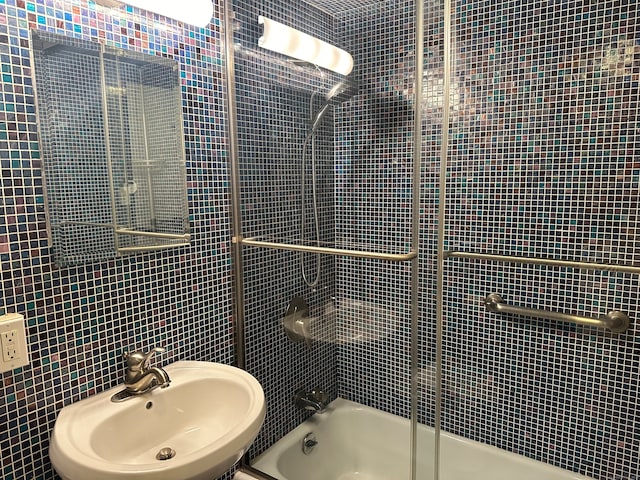 bathroom featuring sink, tile walls, and shower / bath combination with glass door