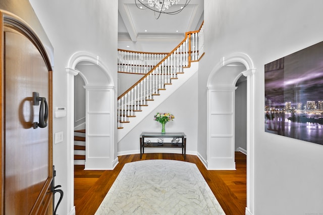 entryway featuring beamed ceiling, dark hardwood / wood-style floors, ornate columns, and a notable chandelier