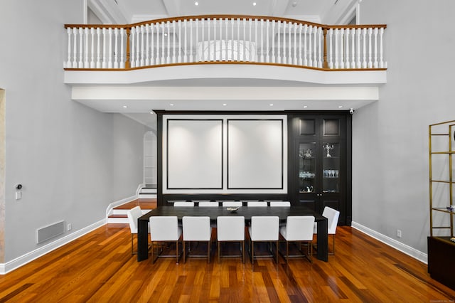 home theater featuring dark hardwood / wood-style flooring and a towering ceiling