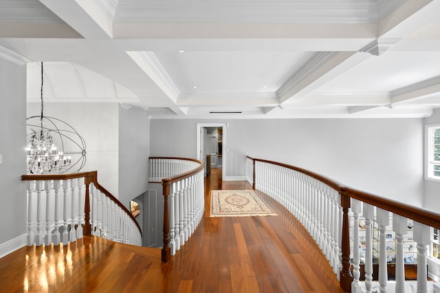 hall with hardwood / wood-style flooring, beamed ceiling, ornamental molding, an inviting chandelier, and coffered ceiling