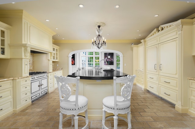 kitchen with a kitchen island with sink, cream cabinets, pendant lighting, and crown molding