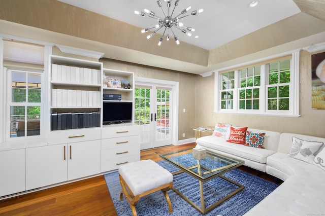 living room featuring dark wood-type flooring, a chandelier, and a tray ceiling