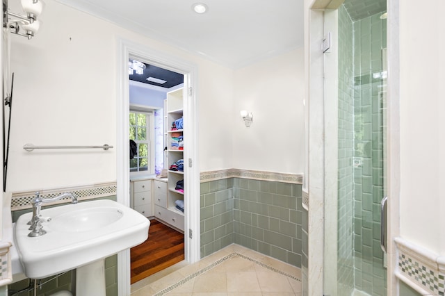 bathroom with ornamental molding, tile walls, tile patterned floors, and a shower with door