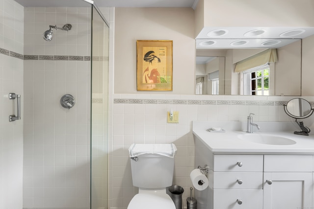 bathroom featuring vanity, toilet, tile walls, and a shower with shower door