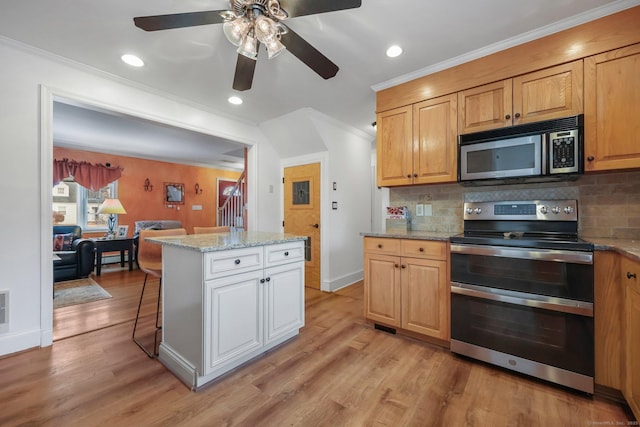 kitchen featuring appliances with stainless steel finishes, tasteful backsplash, light stone counters, crown molding, and a center island