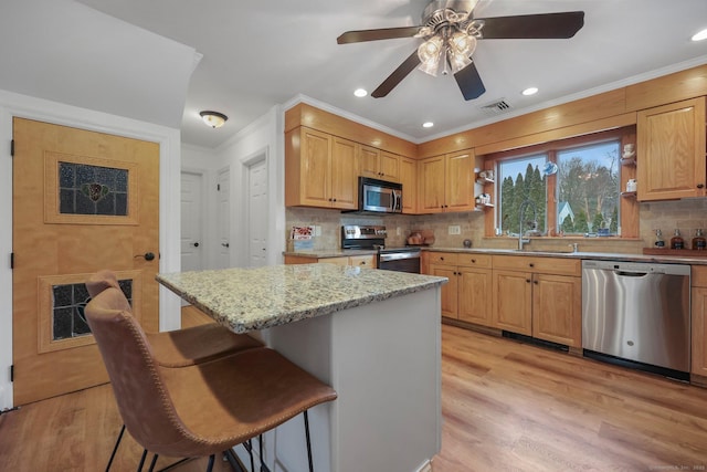 kitchen featuring a breakfast bar, sink, tasteful backsplash, a kitchen island, and stainless steel appliances