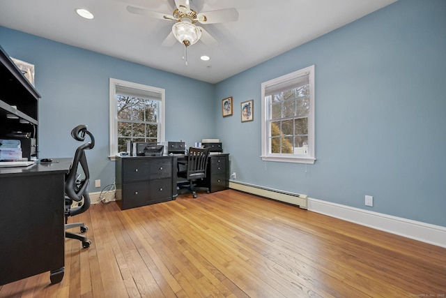 office featuring a healthy amount of sunlight, ceiling fan, a baseboard radiator, and wood-type flooring