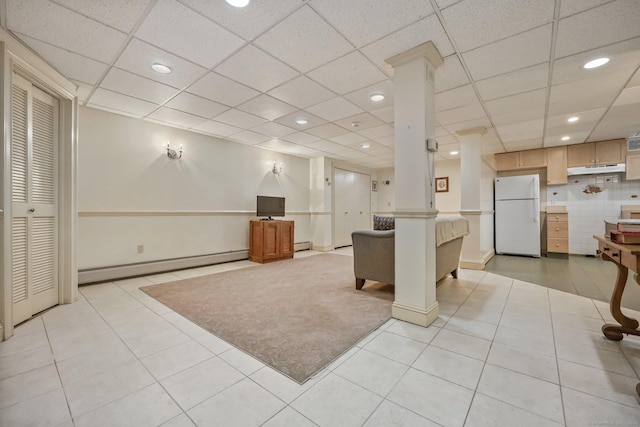 kitchen with a paneled ceiling, a baseboard heating unit, light brown cabinets, white fridge, and light tile patterned flooring