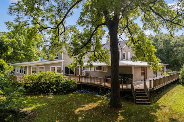 rear view of house featuring a wooden deck and a lawn